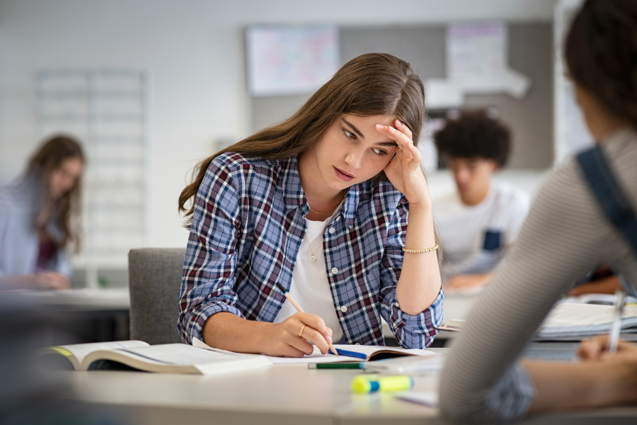 A student sat at a desk leaning their head on their hand