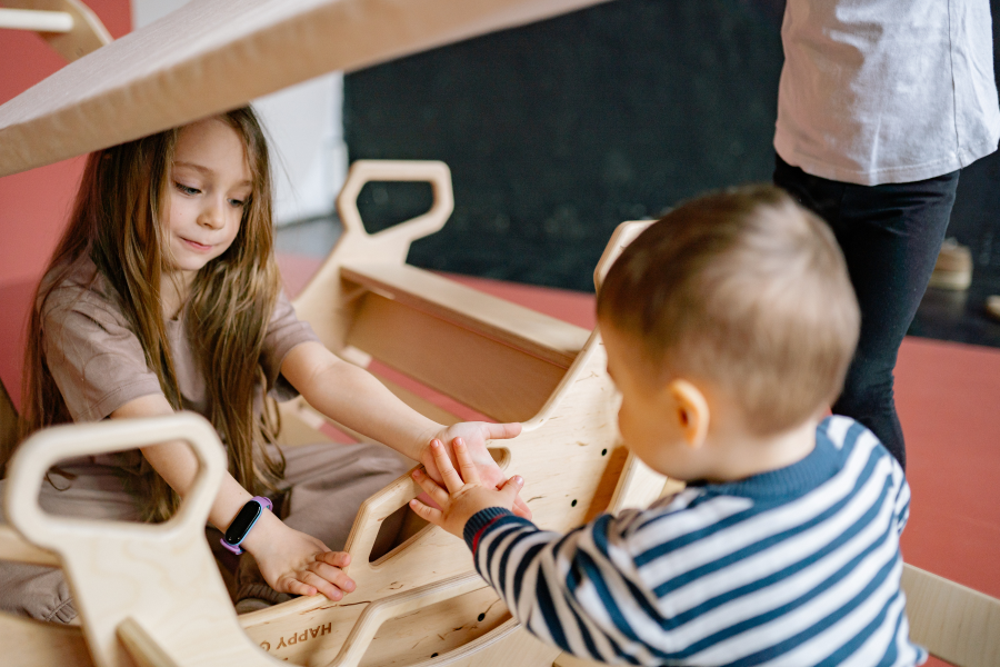 Two young children sat in a wooden toy