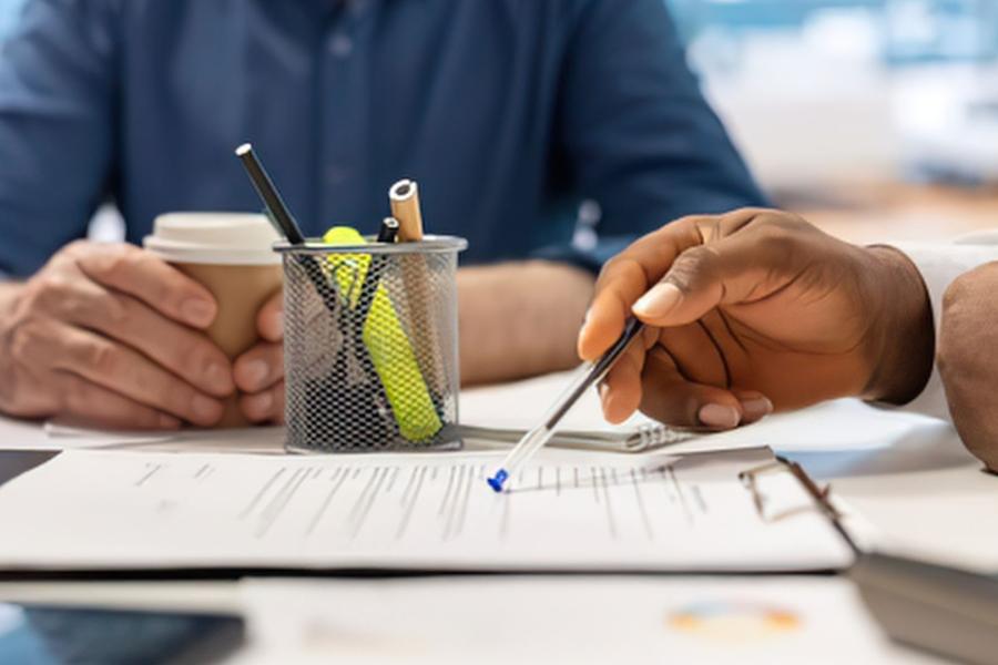 Two people sat around a table with one pointing at a piece of paper
