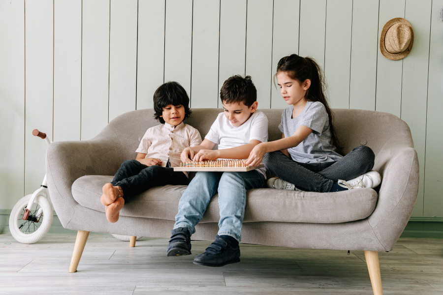 Three children sat on a sofa, playing a game together