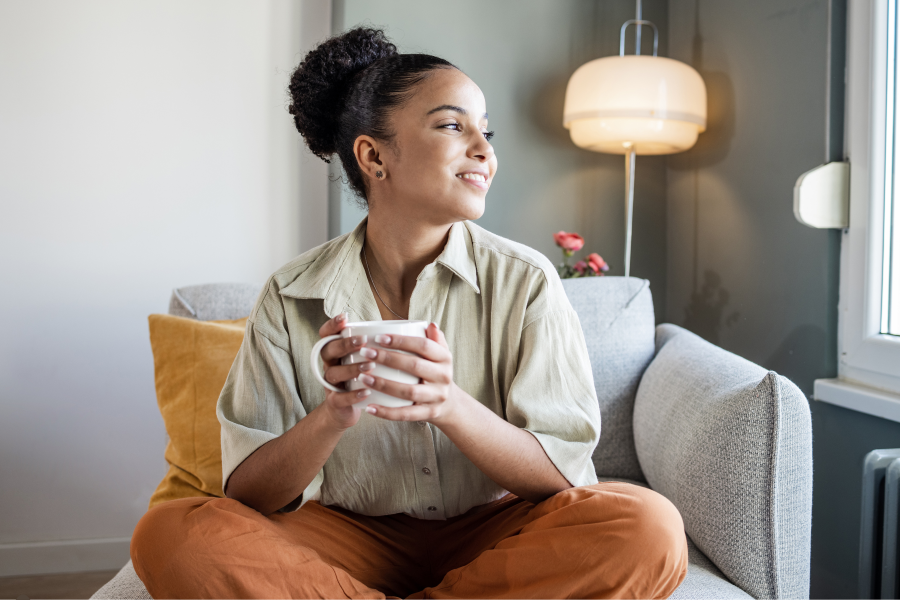 A professional sat on a chair, smiling and holding a mug of tea