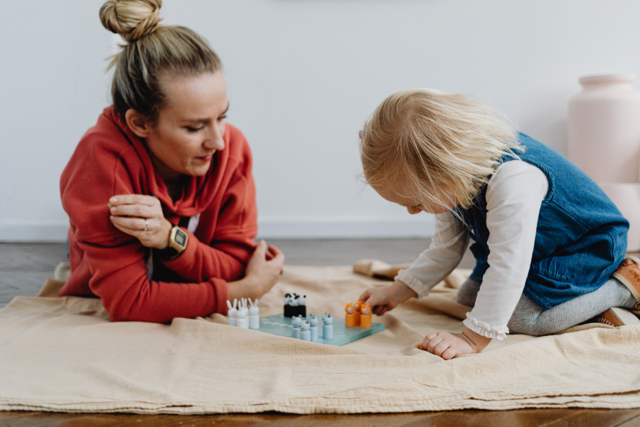 A professional lying on the floor, playing a game with a young child