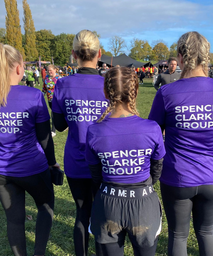The back of four Spencer Clarke Group employees wearing purple t-shirts