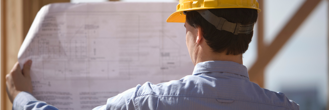 A construction worker looking at plans on paper